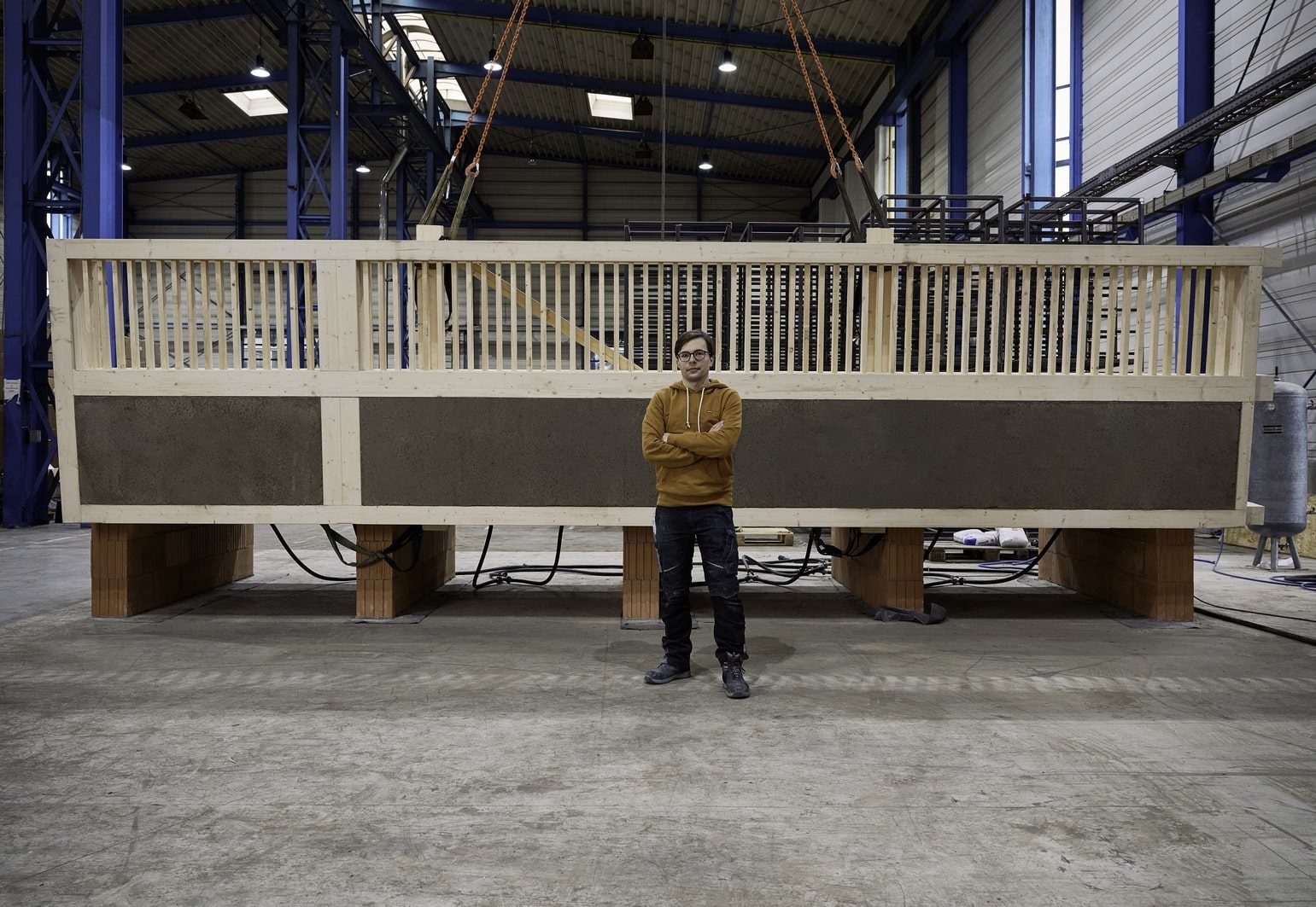 Julian Trummer steht vor der Holz-Lehm Massivdecke, die er während seines Architekturstudiums für nachhaltige Bauteile entworfen hat.