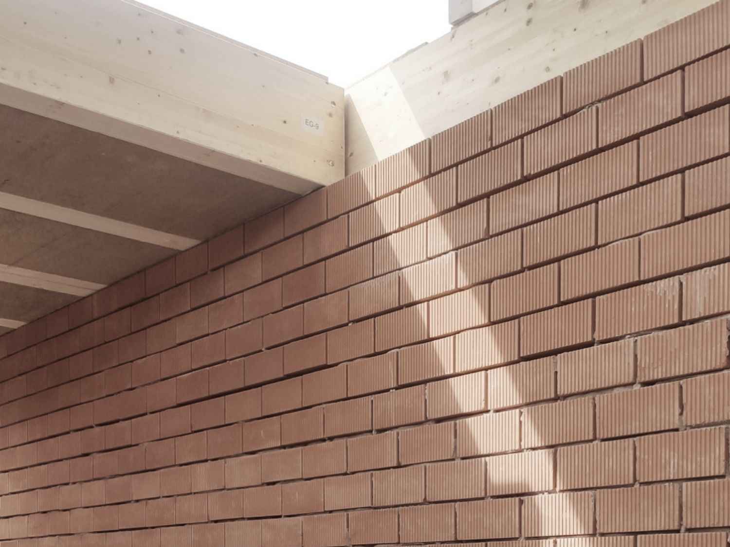 Ziegelwand mit Dach, beleuchtet von einem Licht, das eine warme Atmosphäre schafft.