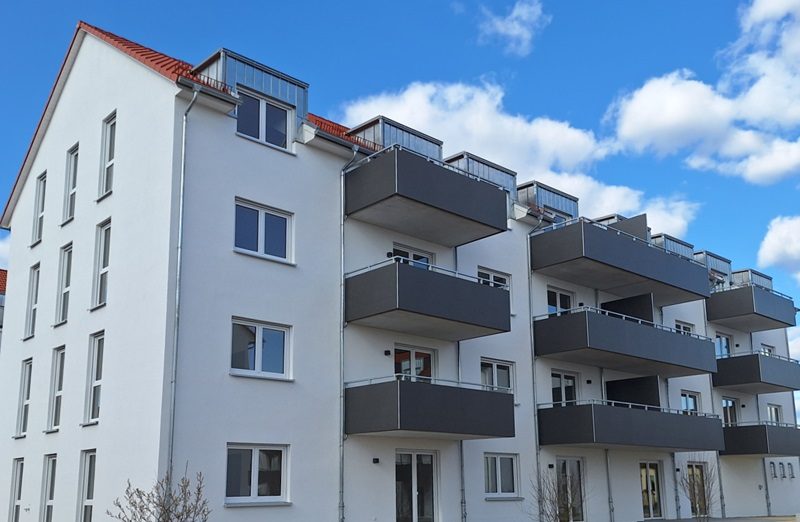 Moderne Wohnanlage gebaut aus Silvacor Ziegelsteine mit weißen Fassaden, roten Satteldächern und mehreren Balkonen unter blauem Himmel in Kulmbach.