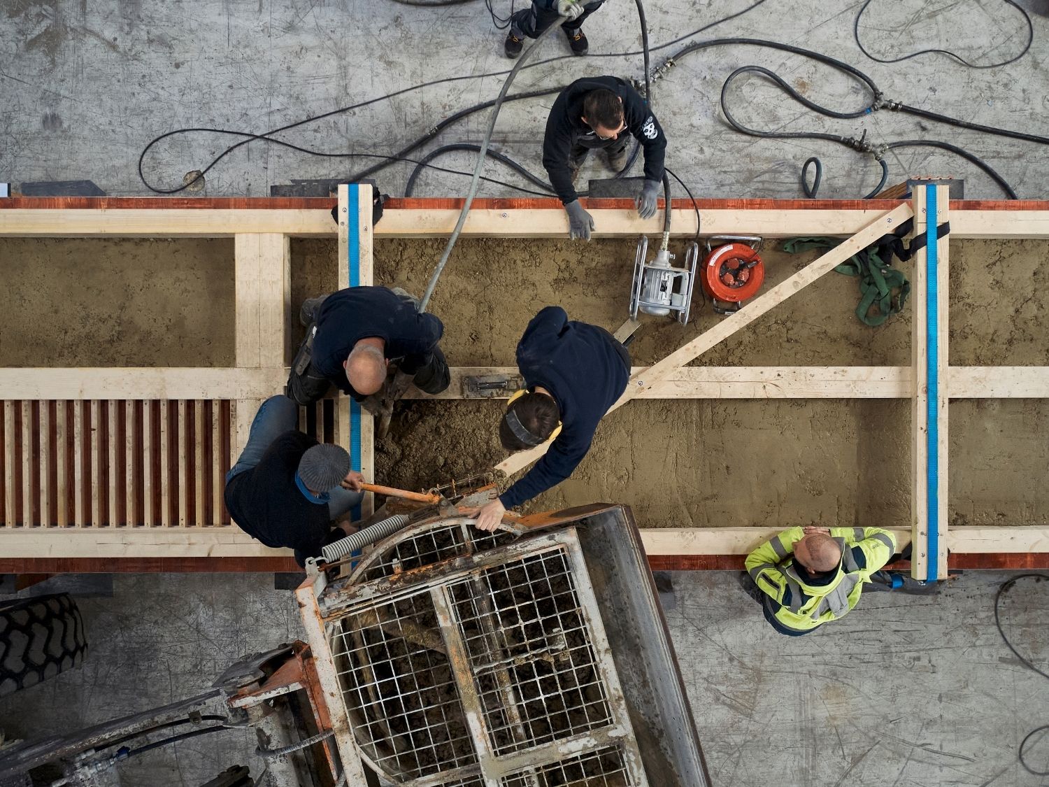 Vier Bauarbeiter verteilen Lehm in eine rechteckige Schalung für eine Holz-Lehm Massivdecke.