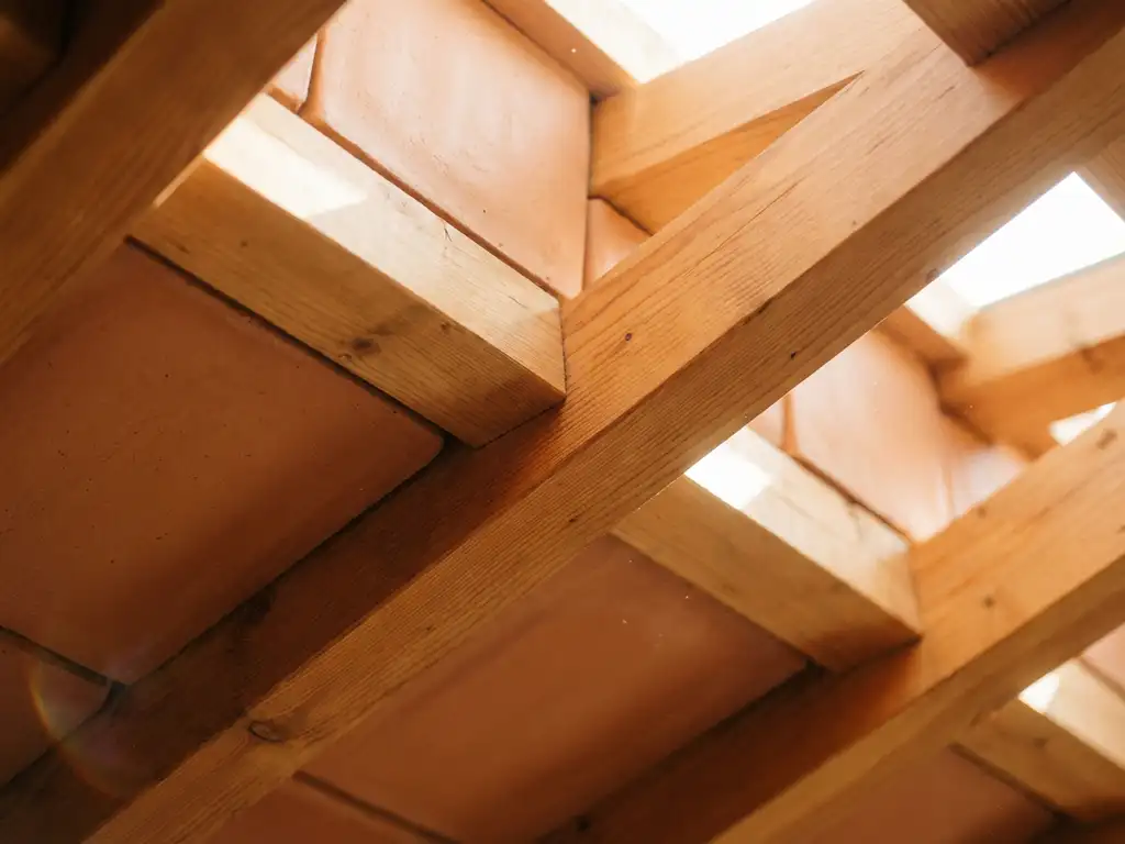 Holz-Lehm-Verbunddecke mit natürlicher Holzmaserung und glatten Lehmplatten in warmen Honig- und Terrakotta-Tönen